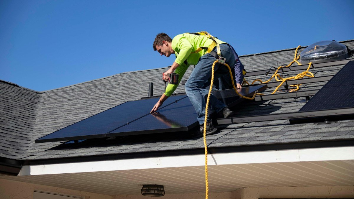 Installer securing a solar panel on a roof